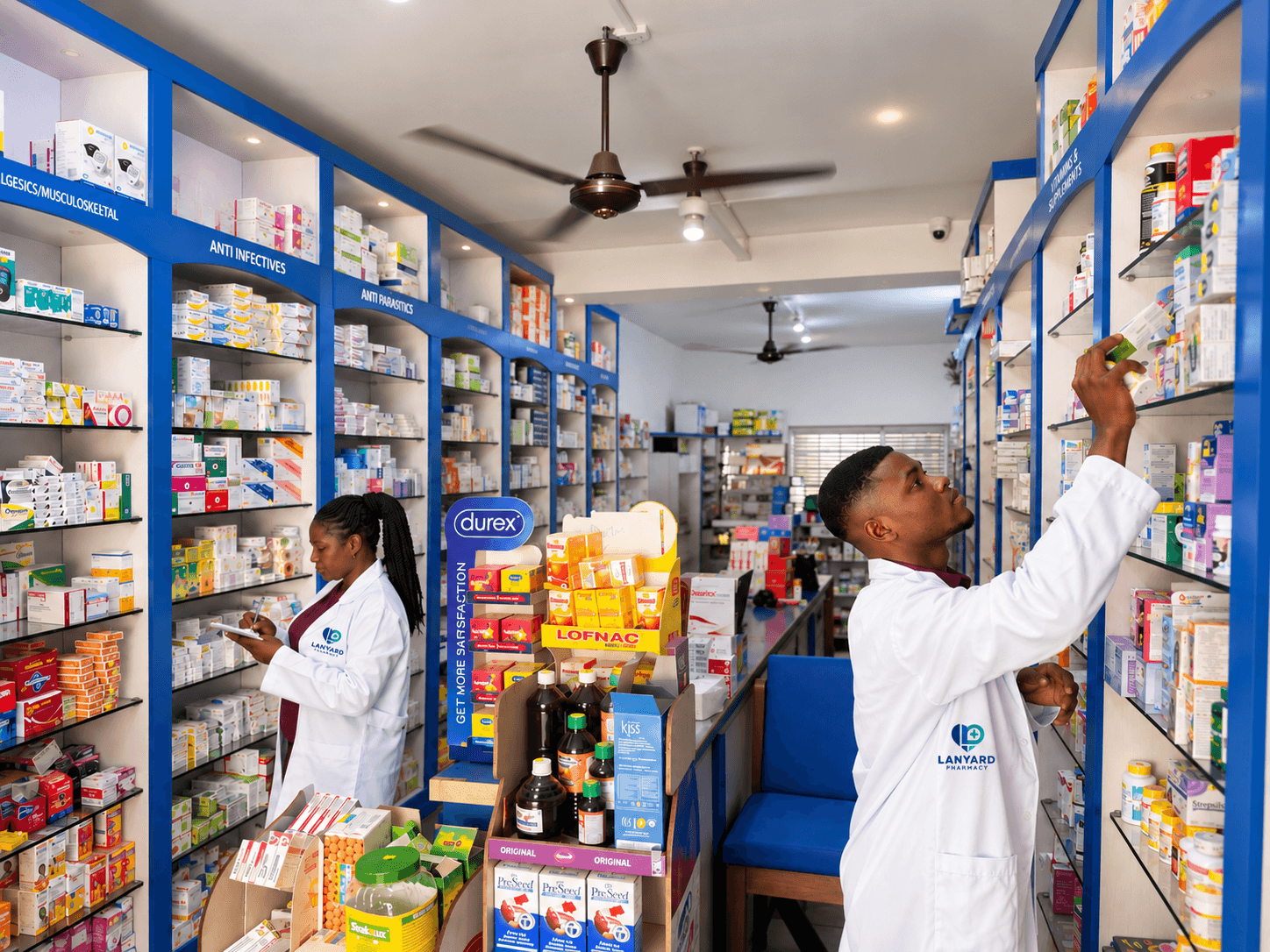 Lanyard pharmacists checking medicines on well-stocked shelves